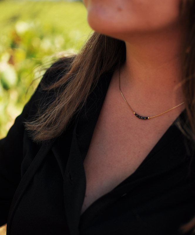 Image portée du collier noir et doré monté sur une chaîne fine dorée